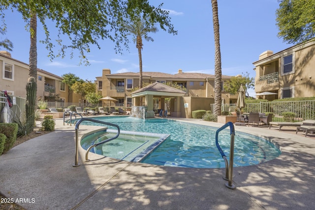 view of pool with fence, a pool with connected hot tub, a gazebo, a residential view, and a patio area