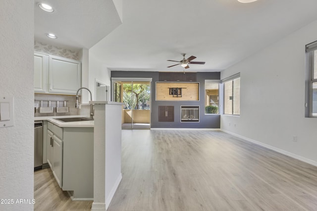 living room with light wood-type flooring, plenty of natural light, a glass covered fireplace, and baseboards