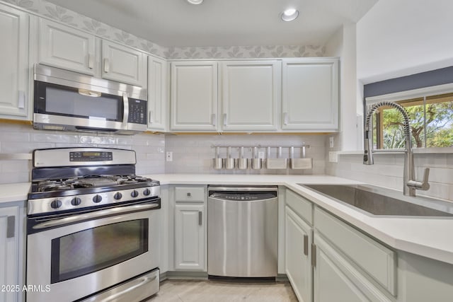 kitchen with stainless steel appliances, a sink, light countertops, and decorative backsplash