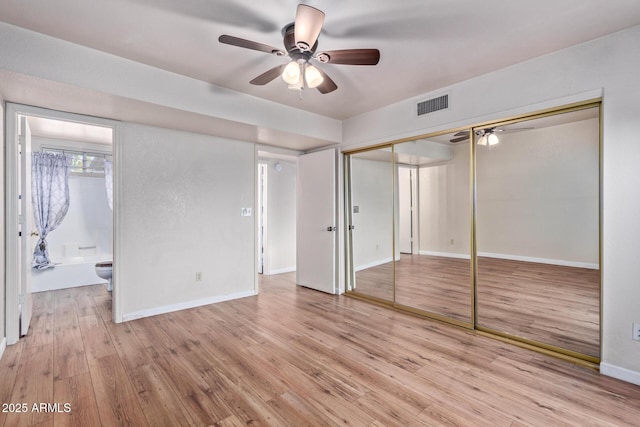 unfurnished bedroom with ceiling fan, light wood-type flooring, and ensuite bath