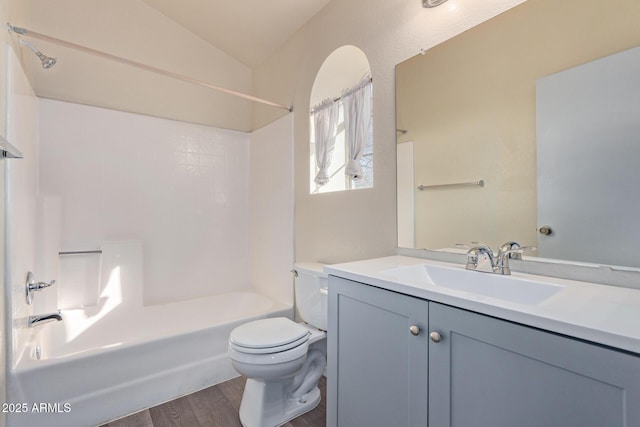 full bathroom with vaulted ceiling, hardwood / wood-style floors, vanity,  shower combination, and toilet