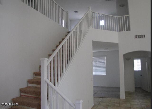 stairs featuring tile patterned floors and a high ceiling