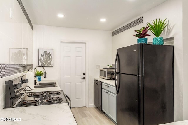 kitchen featuring light hardwood / wood-style flooring, sink, gray cabinets, and appliances with stainless steel finishes