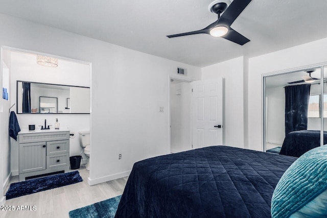 bedroom featuring sink, light hardwood / wood-style flooring, a closet, and ceiling fan