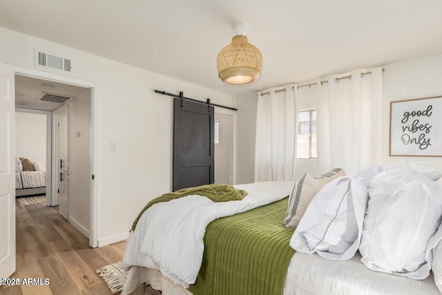 bedroom with hardwood / wood-style floors and a barn door