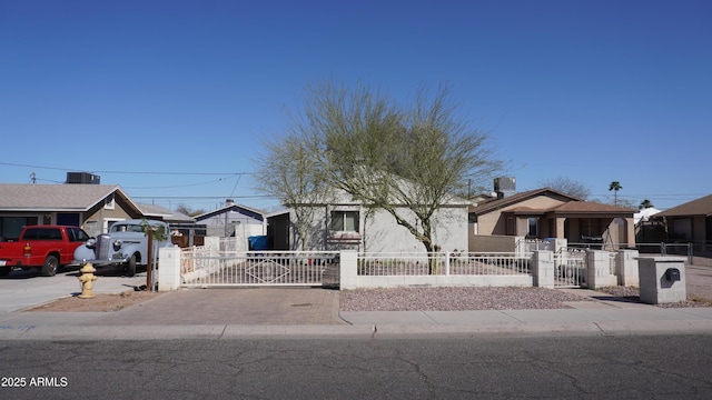 view of front of property with a fenced front yard, a residential view, driveway, and a gate