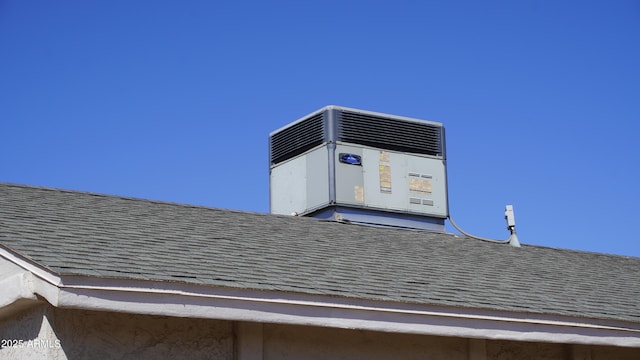 exterior details featuring central AC unit and a shingled roof