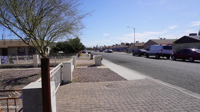 view of road featuring sidewalks, a residential view, curbs, and street lighting