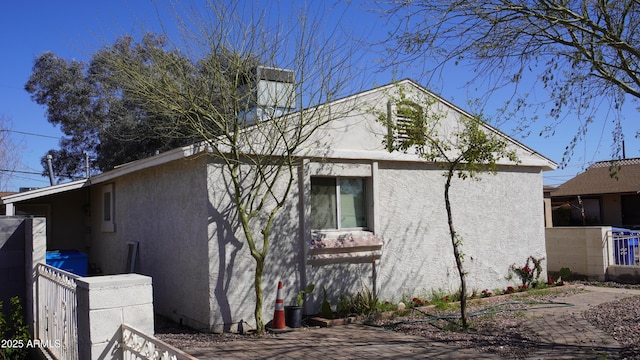 view of side of home featuring fence and stucco siding