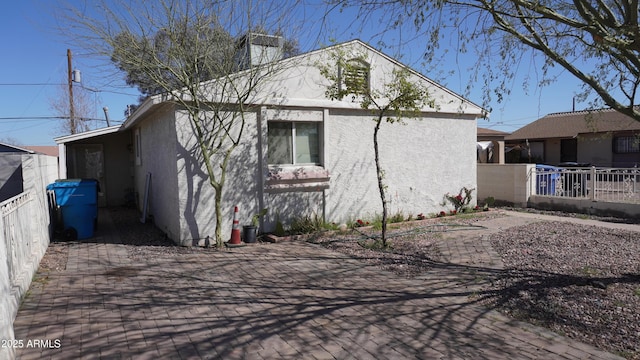 rear view of property featuring fence, a chimney, and stucco siding