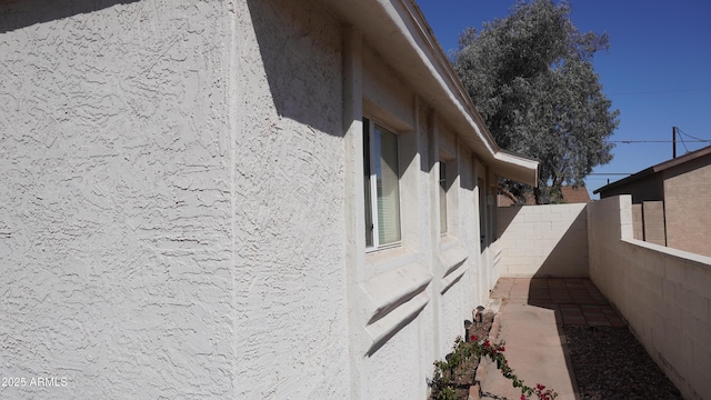 view of side of property featuring stucco siding and a fenced backyard