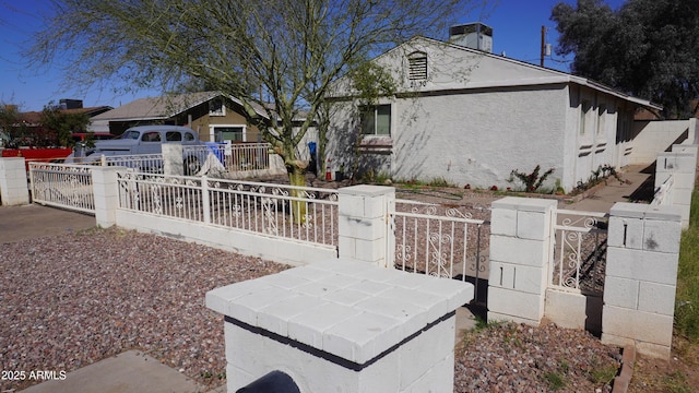 view of front of home featuring a fenced front yard, central air condition unit, stucco siding, and a gate