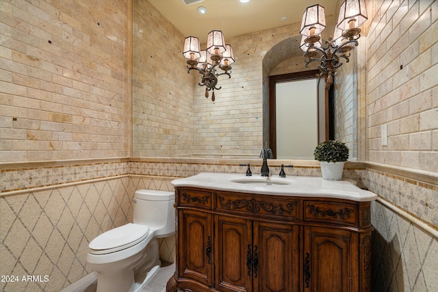 bathroom featuring toilet, vanity, and tile walls