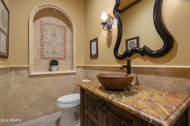 bathroom with toilet, tile walls, and vanity