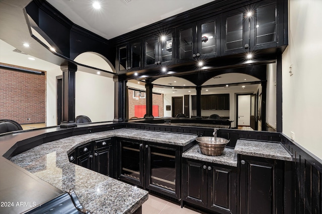 interior space featuring dark stone counters, light tile patterned flooring, a high ceiling, and decorative columns