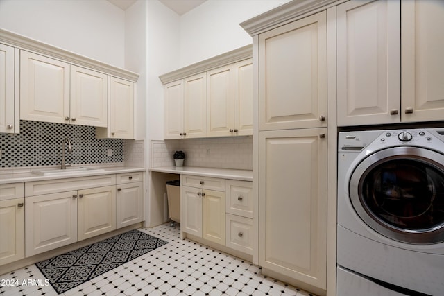 clothes washing area with sink, washer / dryer, and cabinets