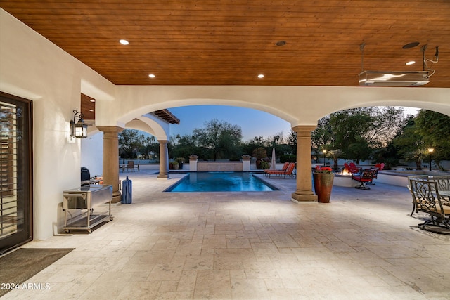 pool at dusk with pool water feature and a patio