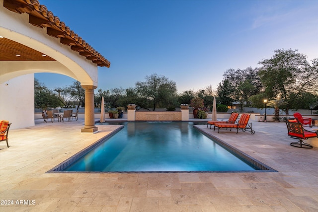 pool at dusk featuring a patio area