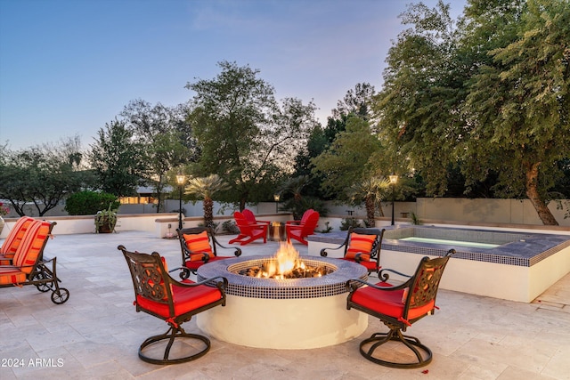 patio terrace at dusk featuring a jacuzzi and an outdoor fire pit