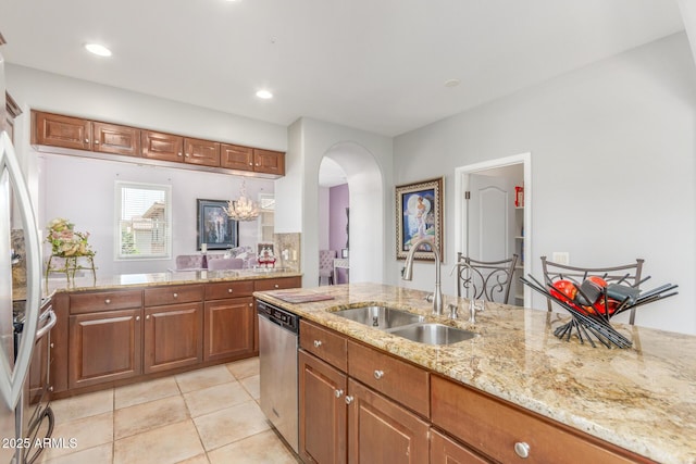 905 S Osborn Ln, Gilbert, AZ 85296 - kitchen with dishwasher, light tile patterned flooring, light stone countertops, arched walkways, and brown cabinetry