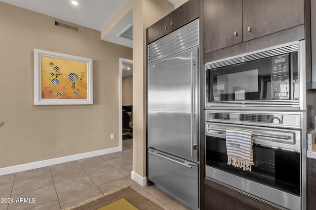 kitchen featuring built in appliances, dark brown cabinetry, and light tile floors