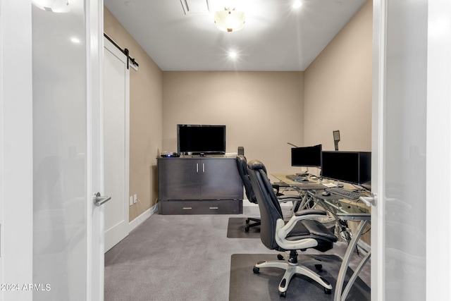 carpeted home office featuring a barn door