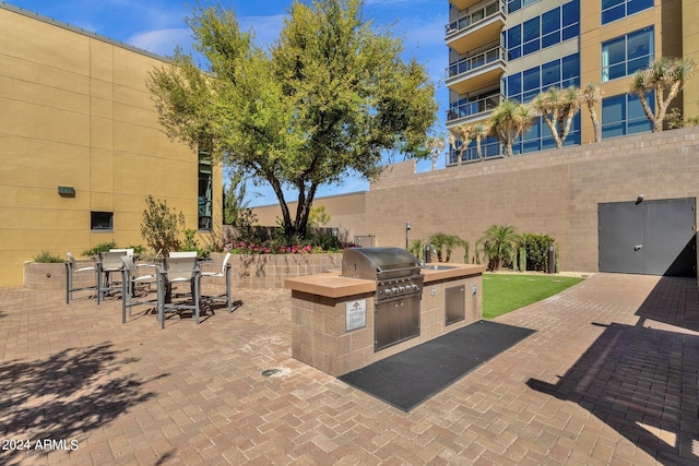 view of terrace with a balcony, area for grilling, and exterior kitchen