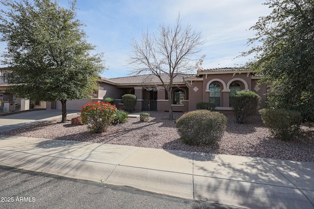 view of front of home with a tiled roof, concrete driveway, and stucco siding