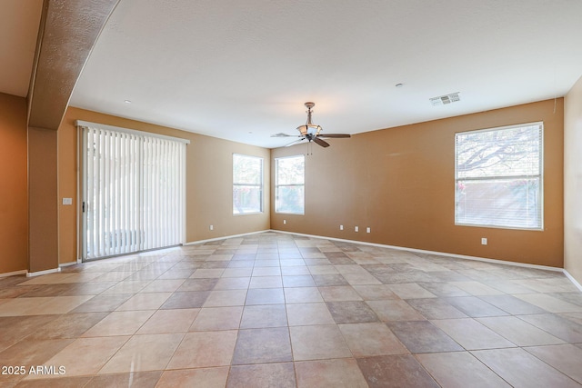 empty room with light tile patterned floors, baseboards, visible vents, and a ceiling fan