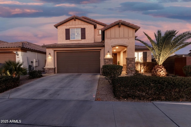 view of front of property with an attached garage, a tile roof, stone siding, concrete driveway, and stucco siding