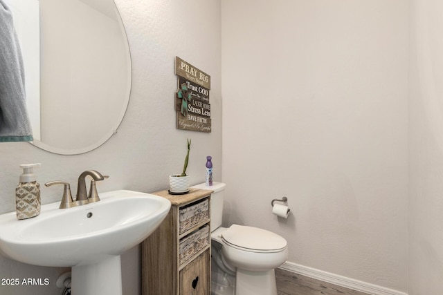 bathroom featuring wood finished floors, a sink, toilet, and baseboards