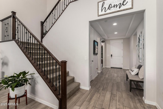 foyer entrance with stairway, baseboards, wood finished floors, and recessed lighting