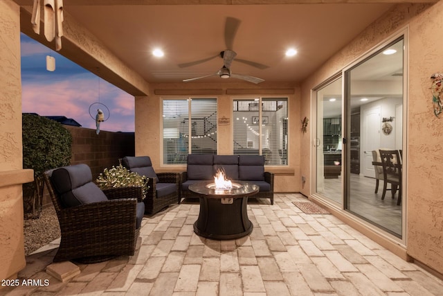 view of patio / terrace with ceiling fan, an outdoor living space with a fire pit, and fence