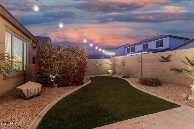 yard at dusk featuring a fenced backyard