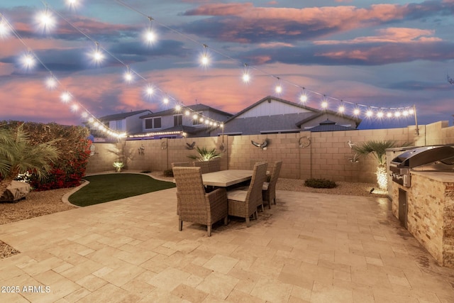 view of patio with exterior kitchen, outdoor dining area, a grill, and a fenced backyard