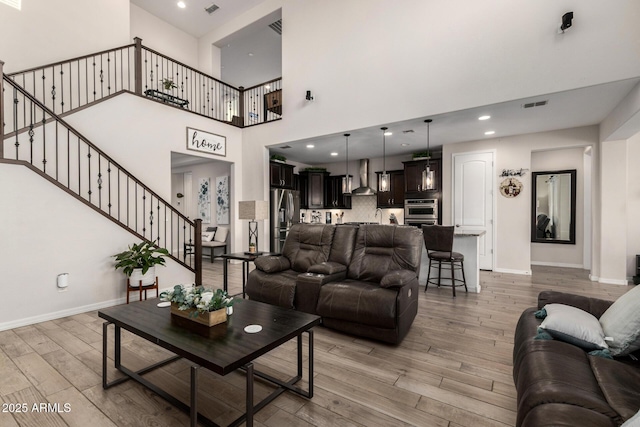 living area featuring recessed lighting, visible vents, light wood-type flooring, baseboards, and stairs