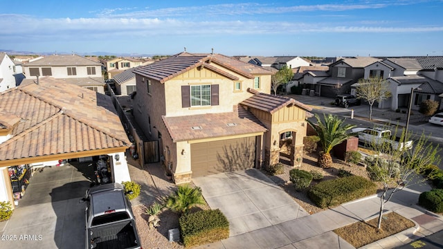 view of front of property with a tile roof, stucco siding, concrete driveway, an attached garage, and a residential view