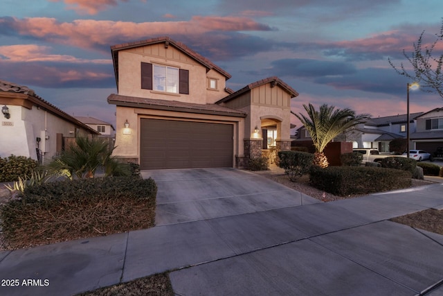 view of front of house with a garage, concrete driveway, stone siding, a tiled roof, and stucco siding