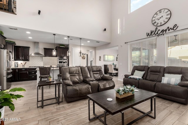 living area with light wood-type flooring, visible vents, and baseboards