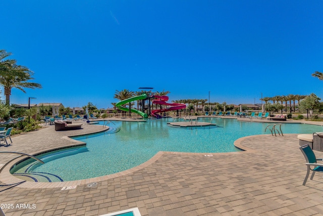 community pool with a patio area and a water slide