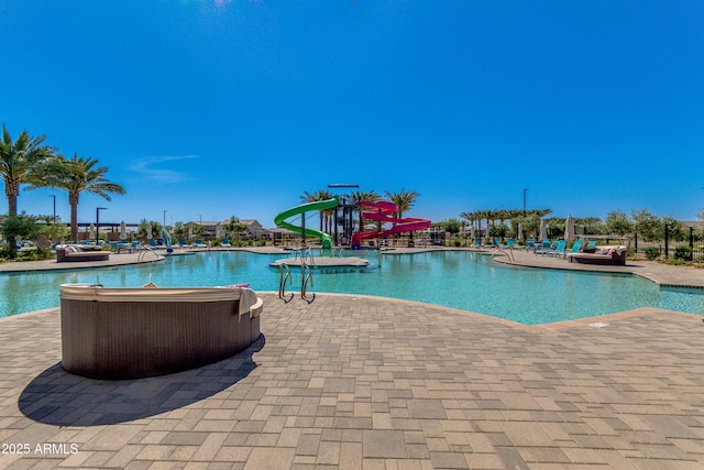 community pool with a water view, a patio area, and a water slide