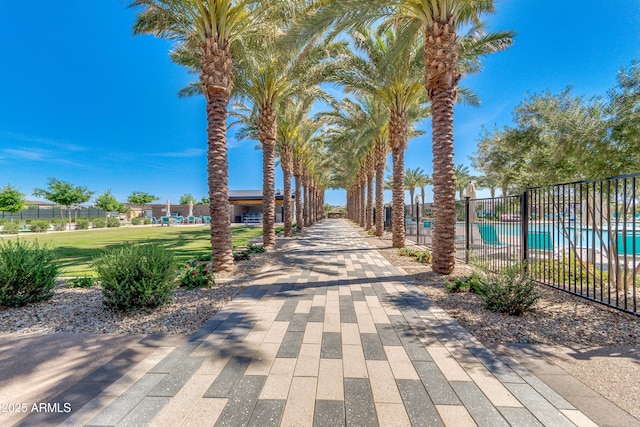 view of property's community featuring fence, a pool, and a lawn