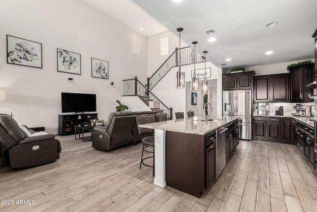 kitchen featuring visible vents, appliances with stainless steel finishes, open floor plan, a sink, and light wood-type flooring