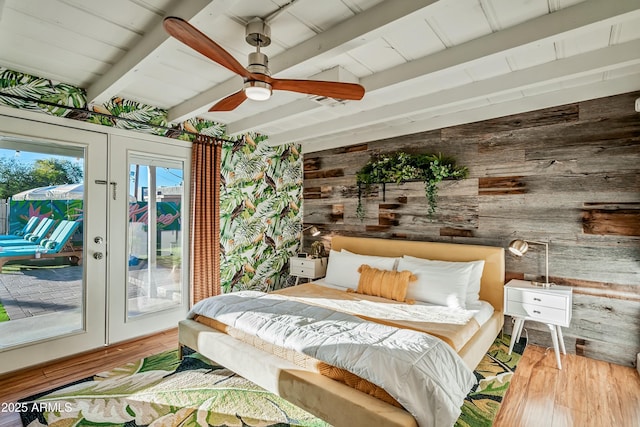 bedroom featuring beam ceiling, ceiling fan, french doors, wood walls, and access to outside