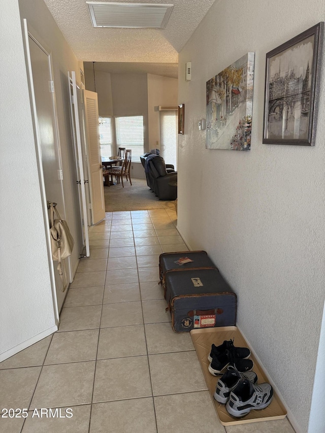 hallway with light tile patterned floors and a textured ceiling