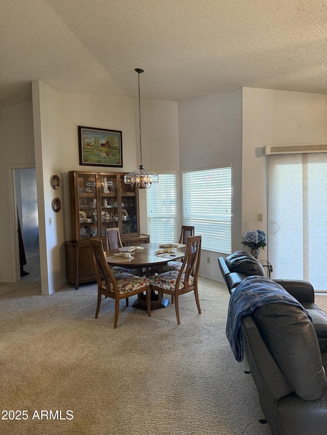 dining space featuring an inviting chandelier, a textured ceiling, and carpet