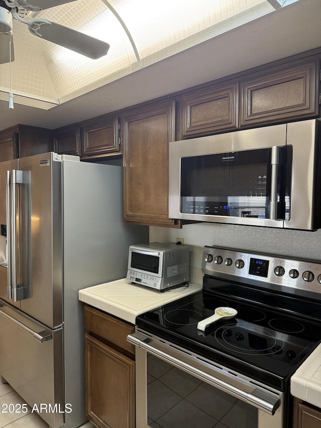 kitchen with ceiling fan, appliances with stainless steel finishes, and dark brown cabinets