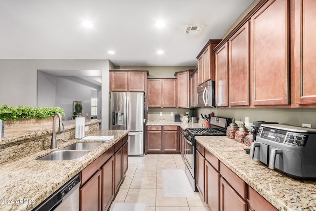 kitchen with light stone countertops, light tile patterned floors, stainless steel appliances, and sink