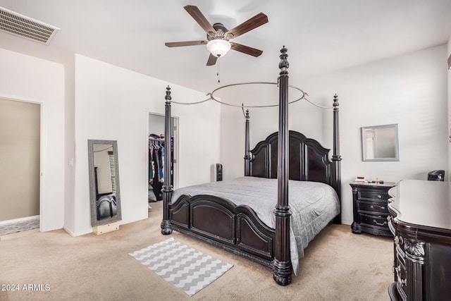 bedroom featuring ceiling fan, a walk in closet, light carpet, and a closet