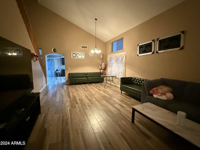 living room featuring hardwood / wood-style flooring, high vaulted ceiling, and a notable chandelier